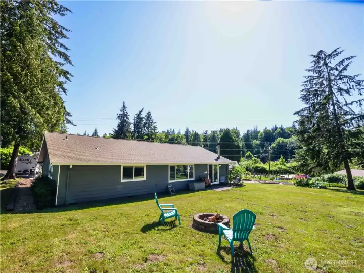 Back of house and yard with fire pit