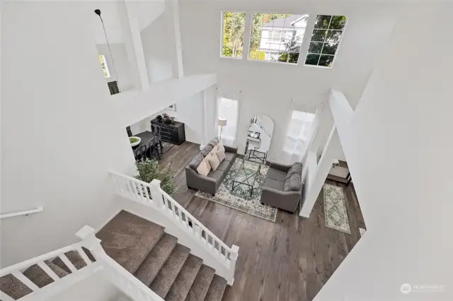 View from the upper level landing to the main floor showcases the expansive vaulted ceilings and large windows that allow for plenty of natural light