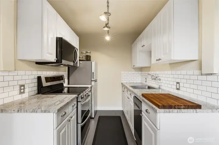 Updated kitchen with modern appliances and stone countertop.