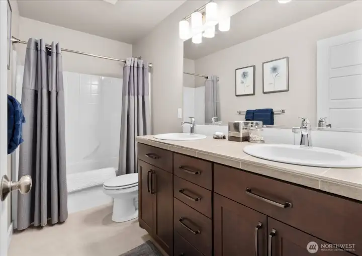 The upstairs guest bathroom features a large vanity with dual sinks