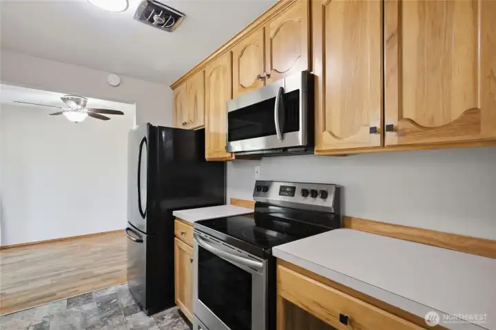 Custom hickory cabinetry pairs with stainless steel appliances and abundant prep space in this bright kitchen. Conveniently positioned adjacent to the dining area with easy access to the covered patio and backyard.