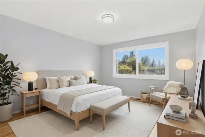 Virtually staged primary bedroom highlighting generous proportions, hardwood floors, and large updated windows overlooking the private backyard. Bright, comfortable, and filled with natural light, this spacious retreat offers flexibility for a variety of furniture layouts.