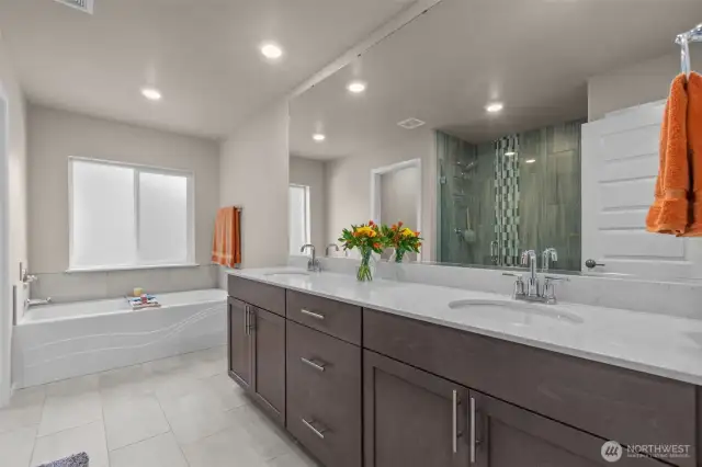 Soaking tub, walk-in shower, and dual vanities in the primary bath.