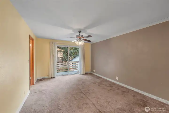 Primary suite bedroom looking towards bathroom and slider to large deck