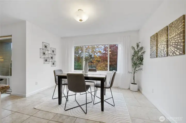 A large dining room window frames views of the surrounding trees, bringing the beauty of each season indoors.