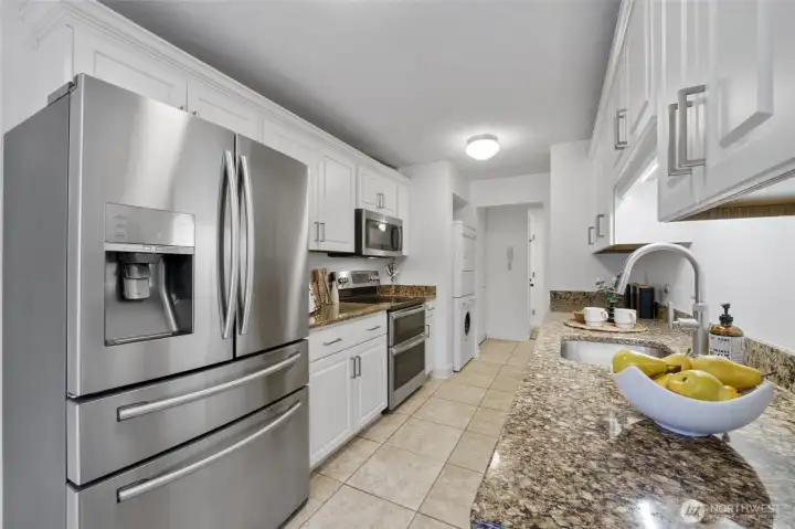 Granite counters, sleek stainless steel appliances, and classic tile flooring create a stylish, cohesive kitchen space.