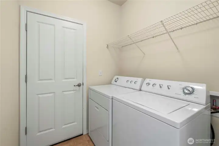 The laundry room leads to the garage and features storage shelves and the washer and dryer included.