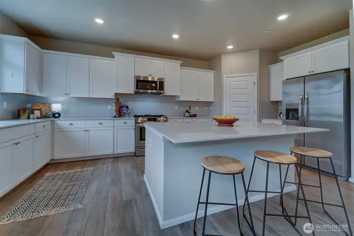 The kitchen has quartz countertops, a tiled subway backsplash, a gas stove/oven, stainless steel appliances, and pantry.