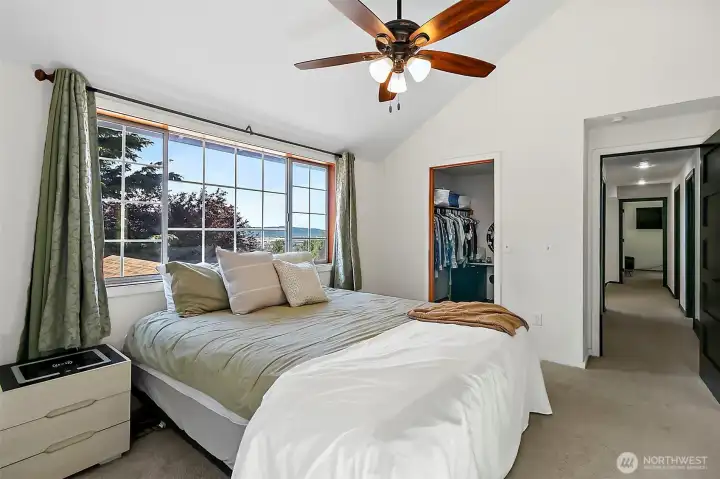 Secluded primary bedroom with ceiling fan and large windows.