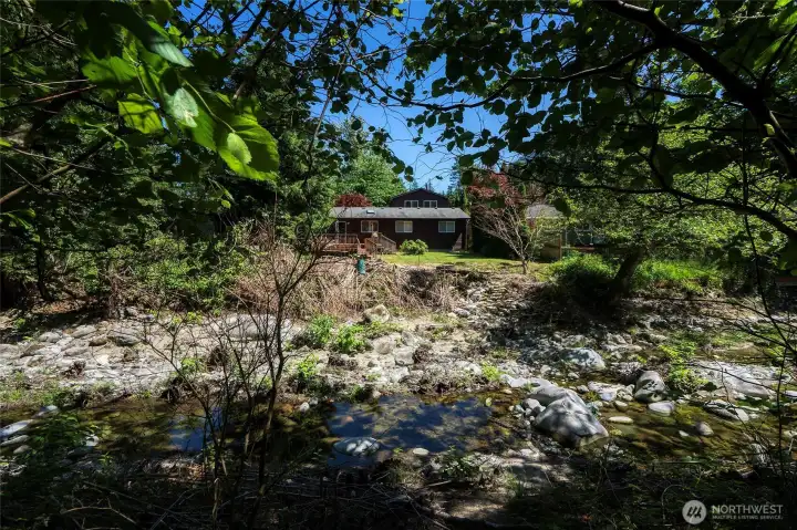 Your backyard captured from the creek, highlighting the serene, wooded setting. Property is fenced on two sides w/fence & greenery for added privacy. Your backyard captured from the creek, highlighting the serene, wooded setting. Property is fenced on two sides w/fence & greenery for added privacy.