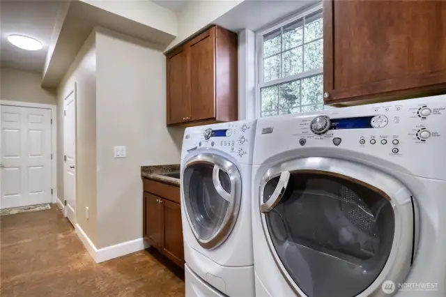 Laundry room has front loading G.E. Profile washer/dryer with steam de-wrinkle function with pedestals. Stainless steel sink with cabinet and cabinets above. Located on main level.