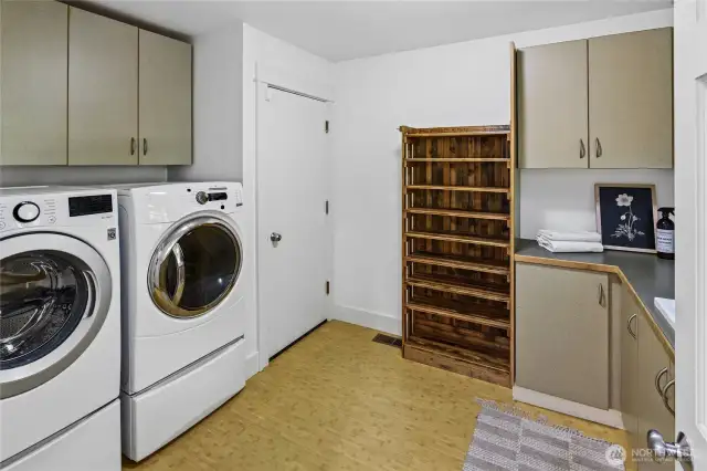 Roomy laundry room with ample storage and shoe rack. Door leads to garage