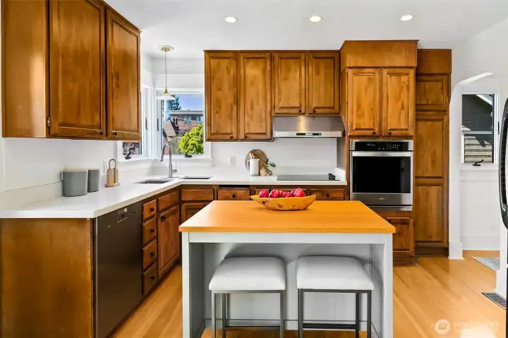 Spacious kitchen is updated with quartz countertops. To the right find a large walk-in pantry and stairs to the lower level.