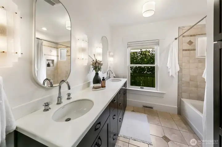 Main level updated bathroom with dual vanity and curated fixtures. Large linen cabinet included to the right.