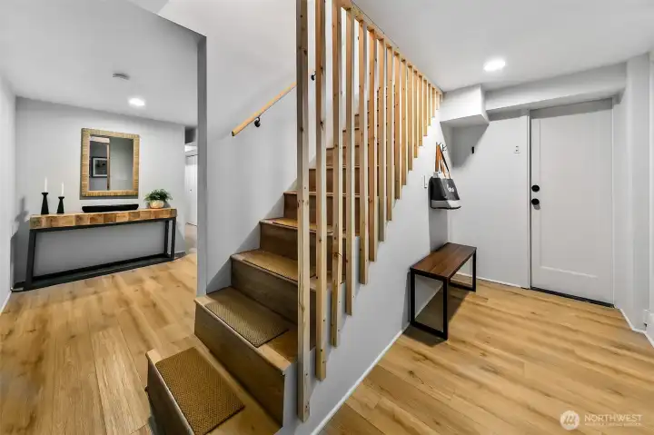 Stairwell to the lower level. To the left find bedrooms and living rooms perfect for extra space, guest and MIL. To the right find the rare attached garage, another entrance + storage.