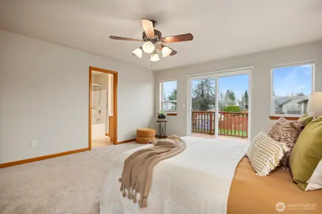 Looking across the primary bedroom toward the full bath and glass sliding door that leads out to the back deck.