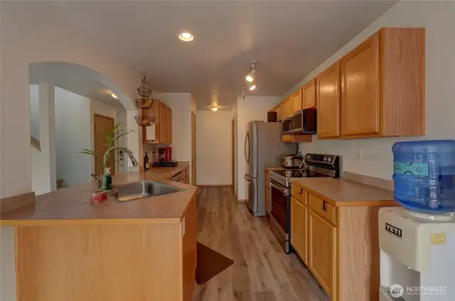 Back in the well designed kitchen. Looking down the kitchen, you'll see the pantry on the left and half-bath waaay down on the right. Looking at the hallway, you can see the coat closet and stairs to the upper floor.