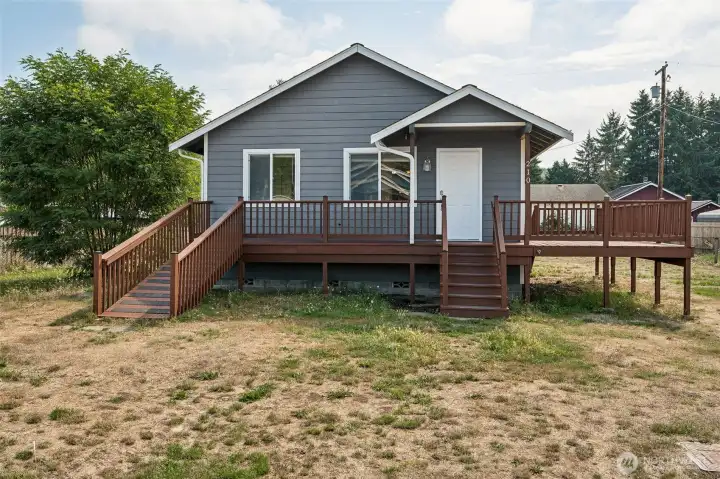 This is the straight-on shot that sells it. Covered entry so you’re not juggling keys in the rain, a natural spot for seating, and a ramp that looks designed, not tacked on. The gray exterior with cedar decks nails that Pacific Northwest look, and it’s basically a blank canvas for your holiday moment.