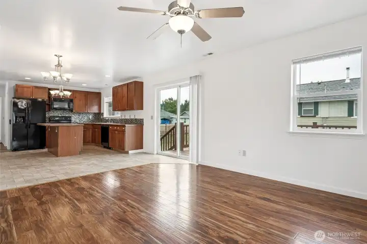This view shows how the living room and kitchen connect, with flooring that transitions from warm plank to neutral cream stone-look vinyl. It’s open but not overwhelming, which means you can carve out a dining area right between the two spaces. The sliding glass door to the deck adds even more breathing room, making this layout feel bigger than it measures.