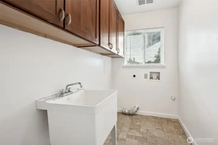 Here’s a laundry setup that works harder than most, with a utility sink, room for a proper washer and dryer, and enough upper shaker cabinets to store everything from detergent to the dog’s treats. Vinyl flooring makes cleanup easy, and the window adds both light and ventilation so it doesn’t feel like a cave.