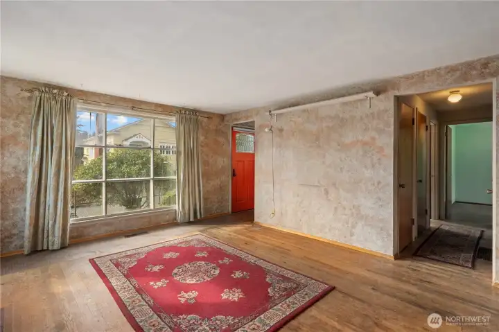 Another view of the living room with a large window overlooking the front yard.