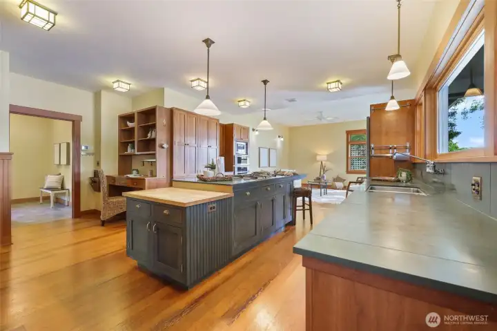 View of the kitchen from dining room. Stone counters, wood cabinets, Meile stainless appliances lead into the family room. Notice the period lighting and switches. Door to the left leads to laundry, bonus room and garage.