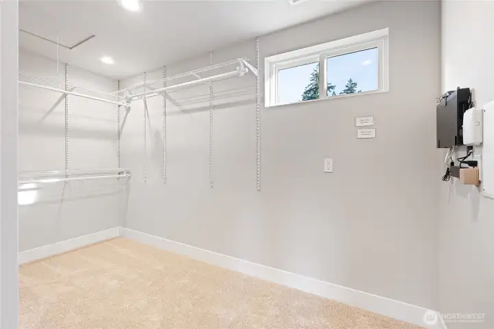 Huge walk-in closet with a window and built-in shelving and hangers.