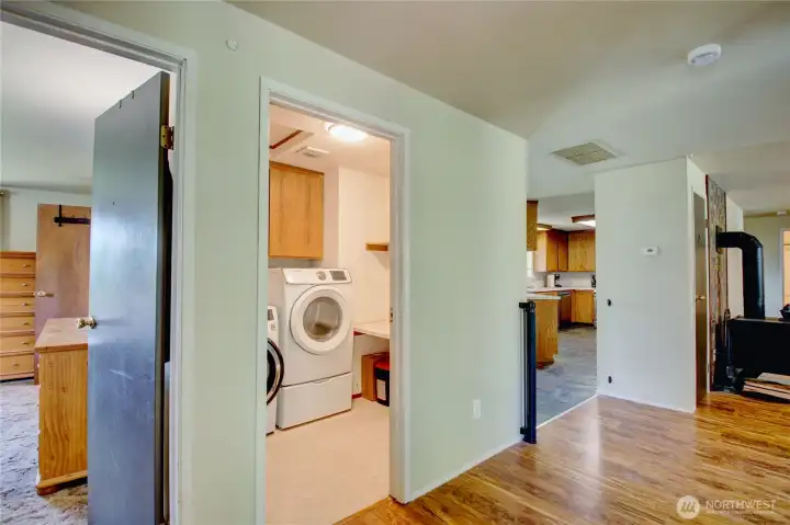 View into primary bedroom, laundry, and kitchen from doorway of bedroom #1. View into primary bedroom, laundry, and kitchen from doorway of bedroom #1.