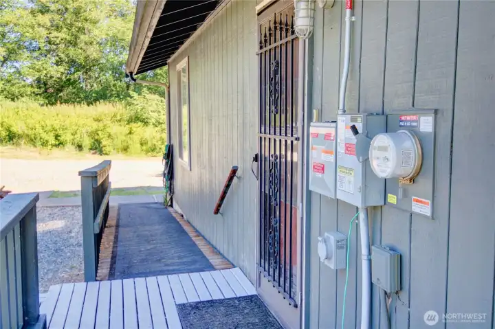 Side door coming off laundry. This part of the porch leads off to the shop a few steps away. You can also see the meter and the solar panel disconnect on the exterior of the home. Side door coming off laundry. This part of the porch leads off to the shop a few steps away. You can also see the meter and the solar panel disconnect on the exterior of the home.
