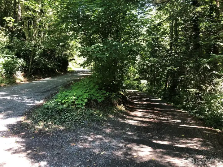 Road on left is primary access road leading down to your dead end drive on right.