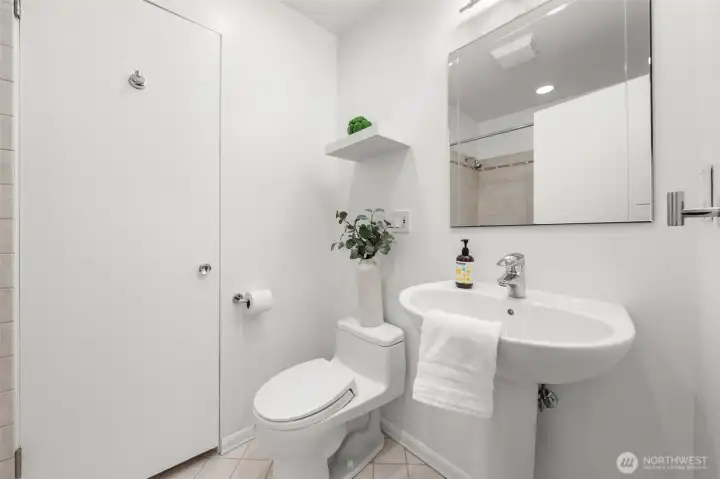 Main bathroom featuring a full tile surround and tub, offering durability and timeless appeal. A dedicated linen closet adds valuable storage while clean, neutral finishes create a polished and functional space.