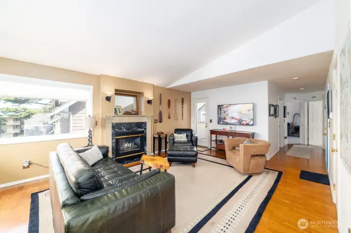 Spacious living room filled with abundant natural light, hardwood floors, and entry to a second outdoor deck