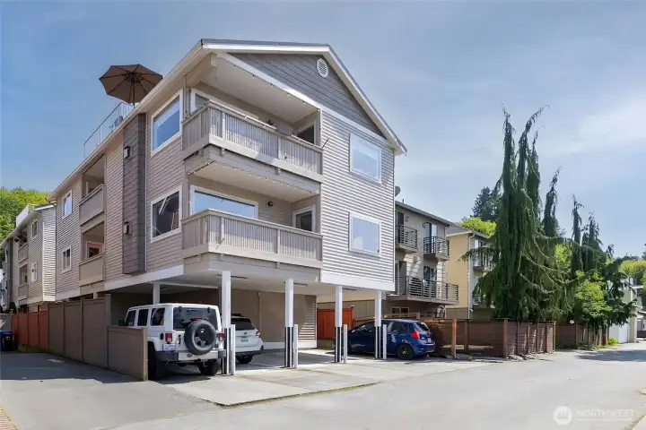 Exterior view of top-floor end unit with dedicated covered parking—the middle carport—ideal for busy Alki summers