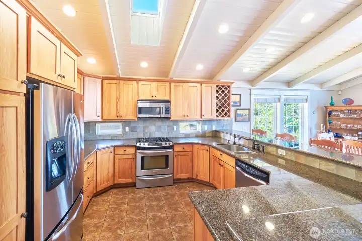 An expansive kitchen features granite countertops, a skylight, and thoughtfully placed windows that illuminate the working space.