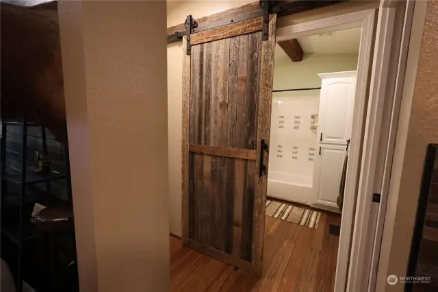 Guest bath with barn door. Tub shower with ceramic tiles.