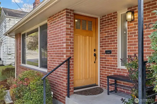 Front door to the house facing west. Covered entry. Note the statement vertical panel design, upper three-light section, exquisite hardware.