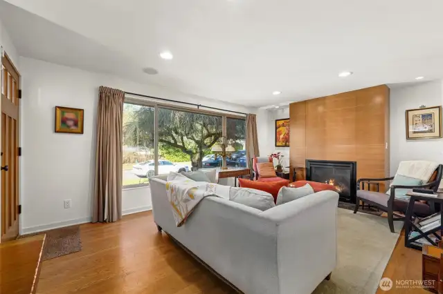 The living room features a wall of windows: fixed center picture window, and sidelights with sliding hardware and screens for fresh air.