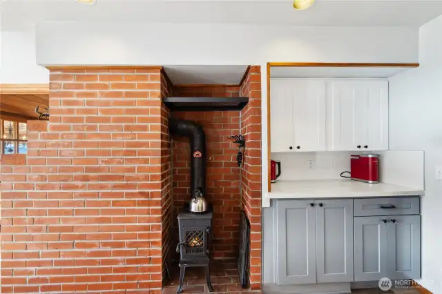 Real wood stove in kitchen on back side of living room fireplace, which is gas.