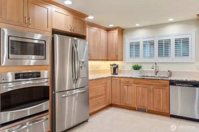 Wall of appliances has everything a cook needs. Cabinets reach to the ceiling and are trimmed with handsome crown moulding. Plantation shutters for a classic, neat look.