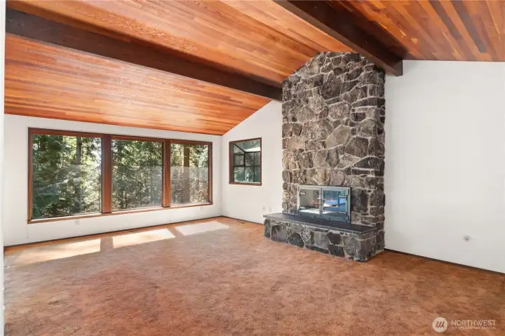 The inviting living room has warm cedar vaulted beamed ceilings and the floor to ceiling fireplace with local Mats Mats Quarry stone.
