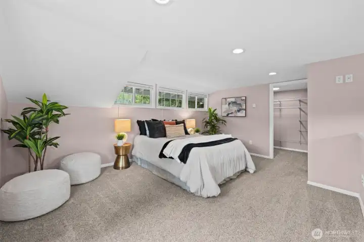 The generous upstairs Primary Suite 2 features a vaulted ceiling, a wall of clerestory windows that fill the room with soft natural light, and a walk-in closet with built-in shelving. The suite offers a true sense of privacy and retreat — the perfect place to decompress at the end of the day.