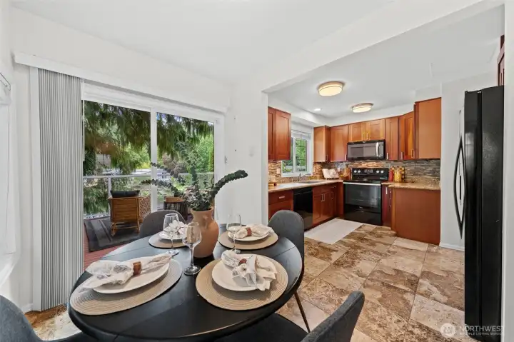 The breakfast nook sits at the heart of the home, connecting the kitchen and the deck through a sliding glass door that invites natural light and fresh air. Granite countertops, rich cherry cabinetry, and a stainless appliance suite are all visible from this vantage point — everything you need for everyday living and easy entertaining.