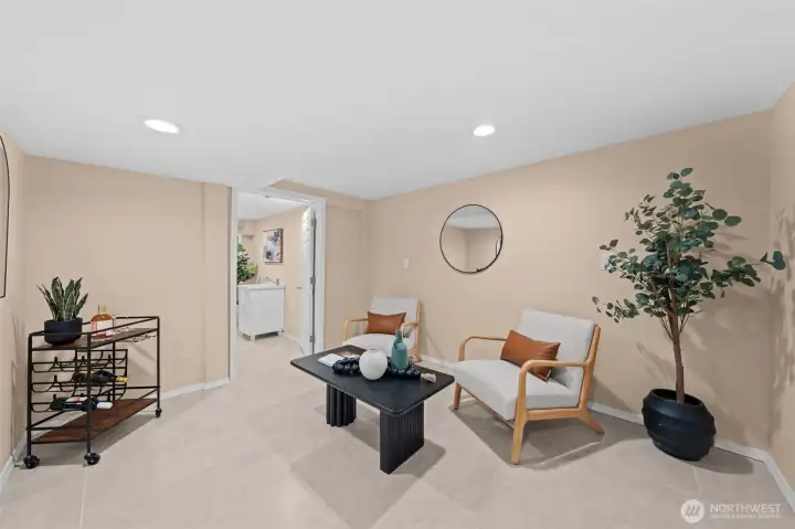 This inviting lower level bonus room offers a flexible layout ready to become whatever you need — a second living space, home office, media lounge, or entertainment room. Recessed lighting, large-format tile flooring, and a warm neutral palette give it a finished, polished feel throughout.