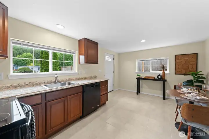 The lower level includes a full secondary kitchen with cherry cabinetry, granite countertops, stainless appliances, and an open living and dining area — ideal for multi-generational living, extended guests, or added rental opportunity. Large windows bring in natural light and connect the space to the outdoor surroundings.