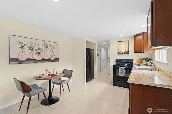 From this angle, the lower level kitchen/dining space/living space reveals a connected layout — a functional  kitchen flows directly into a light-filled breakfast nook, with additional hallway access to the laundry, the backyard, and its private bath.