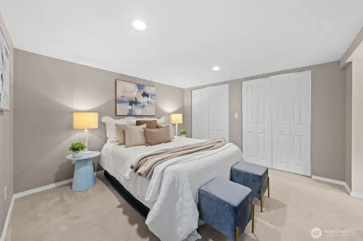 A spacious lower-level third bedroom with plush carpet, recessed lighting, and dual closets offers plenty of room and storage for guests, family, or a work-from-home setup. The neutral palette and generous square footage make this room truly versatile.