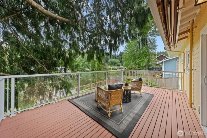 Unwind on this expansive upper deck with sweeping views of the river and tree canopy — a perfect spot for morning coffee or evening gatherings. The glass-panel railing keeps sight lines open while the generous deck surface offers plenty of room for outdoor dining and lounge furniture.