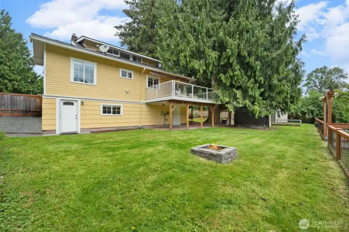 This generous, fully fenced backyard is ready for everything — weekend gatherings around the built-in firepit, lawn games, or simply relaxing in the sun. The elevated deck provides covering for the patio below, mature evergreens lining the property, and easy access to the waterfront gate make this outdoor space truly special.