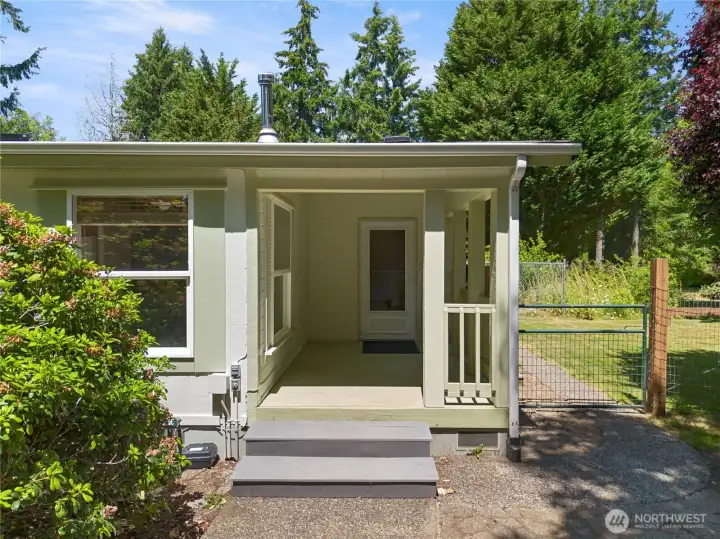 Covered entry with deck and gates that lead to the fenced 1/2 acre behind the home.