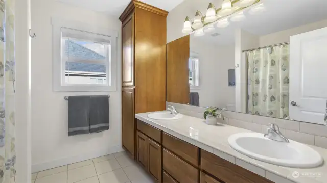 A stylish bathroom featuring wood cabinetry, a spacious sink, and a large mirror.